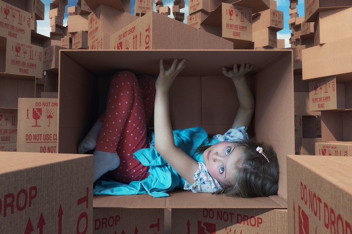 Girl in a box surrounded by cardboard boxes