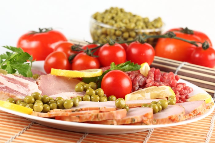 Meat platter with ham, tomatoes, peas, and lemon