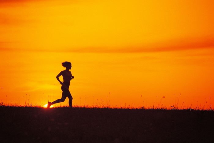 Silhouette of a woman running at sunset