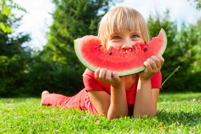 Girl eating watermelon on grass