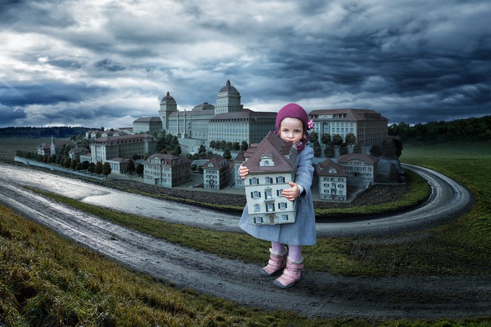 Girl holding a dollhouse in front of a miniature city