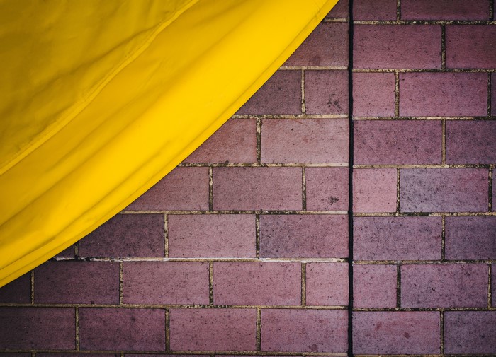 Yellow fabric over brick wall texture