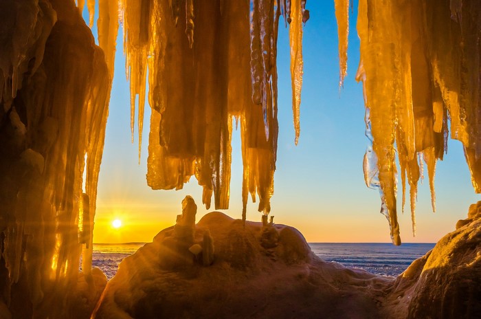 Sunrise over icy sea cave with icicles