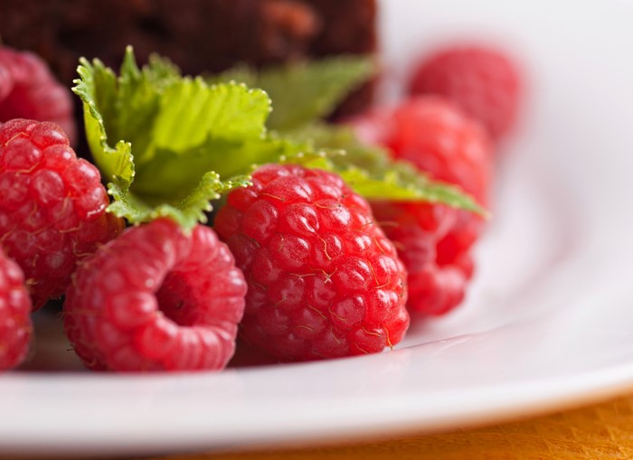 Raspberries and mint on a white plate