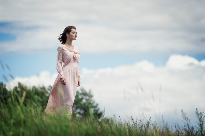 Woman in pink dress standing in a grassy field
