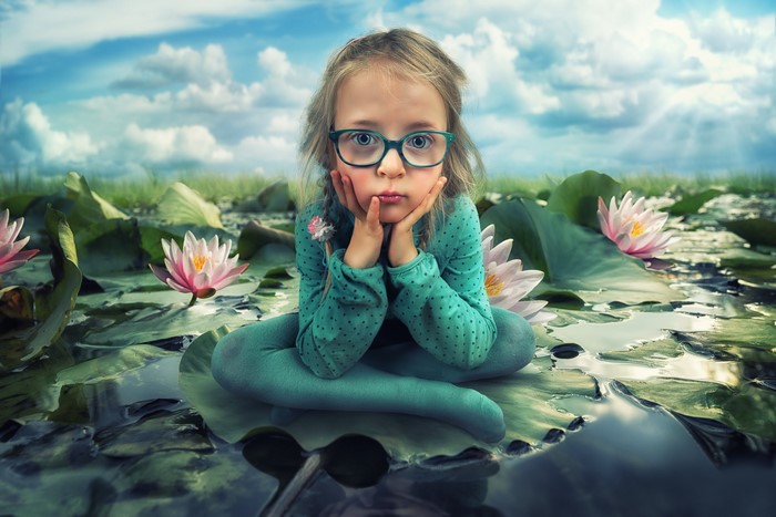 Girl with glasses sitting on lily pad