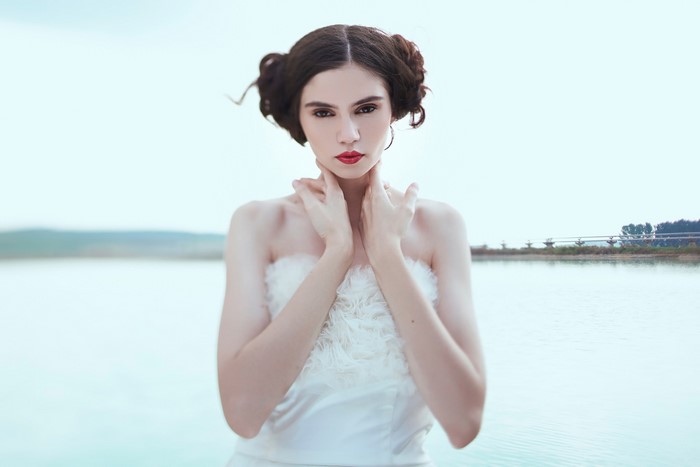 Woman with brown hair and red lipstick by the water