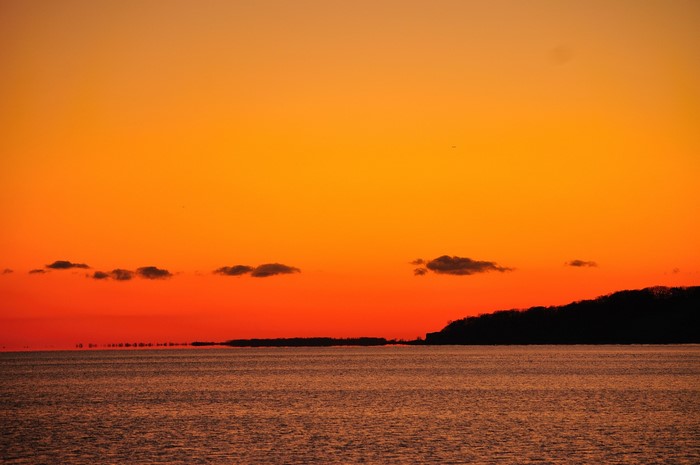 Sunset over the sea with a silhouetted coastline