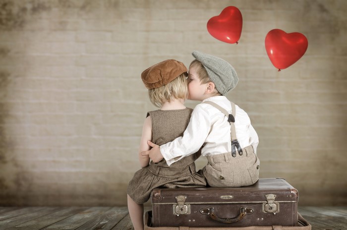 Two children kissing with heart balloons