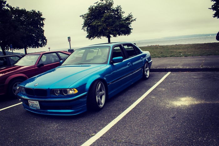 Blue BMW 750il parked by a body of water