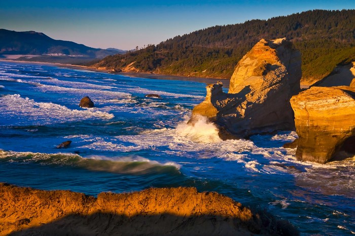 Waves crashing on rocky sea stacks at sunset
