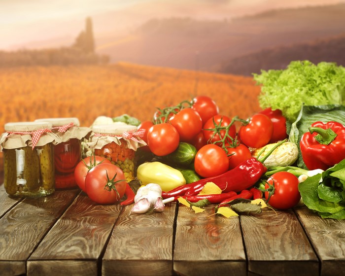 Vegetables and Jars on Wooden Planks with Field Background