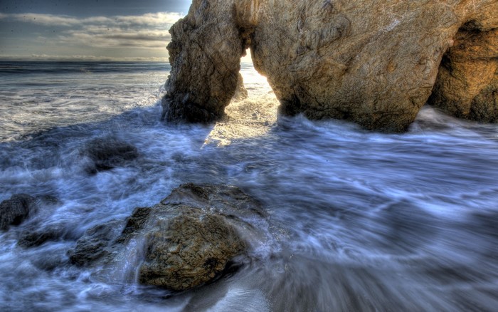 Ocean waves crashing through a rock archway