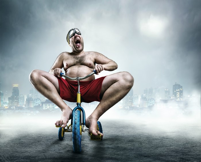 Man in goggles riding a tricycle in a city