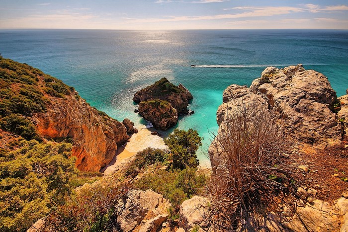 Rocky coast overlooking a turquoise bay with a boat