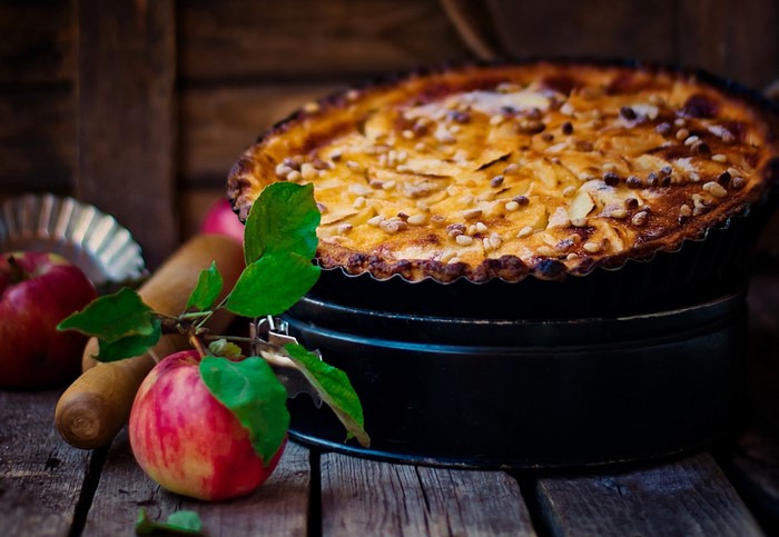Apple pie with nuts and apples on a wooden table