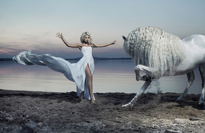 Blonde woman in white dress with white horse