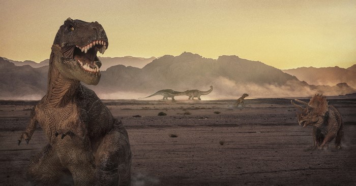 Dinosaurs in a desert landscape at sunset