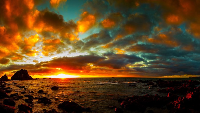 Sunset over rocky coast with dramatic clouds