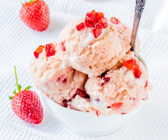 Strawberry ice cream in a bowl with fresh strawberries