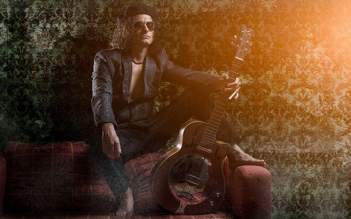 Man with guitar sitting on a sofa