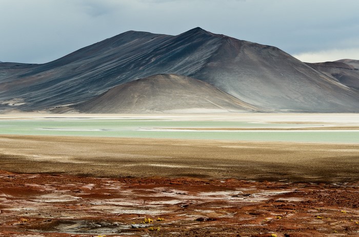 Volcanic mountains and a green lake in a barren landscape