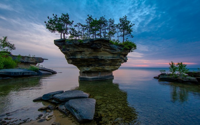 Rock formation with trees in the sea at sunrise