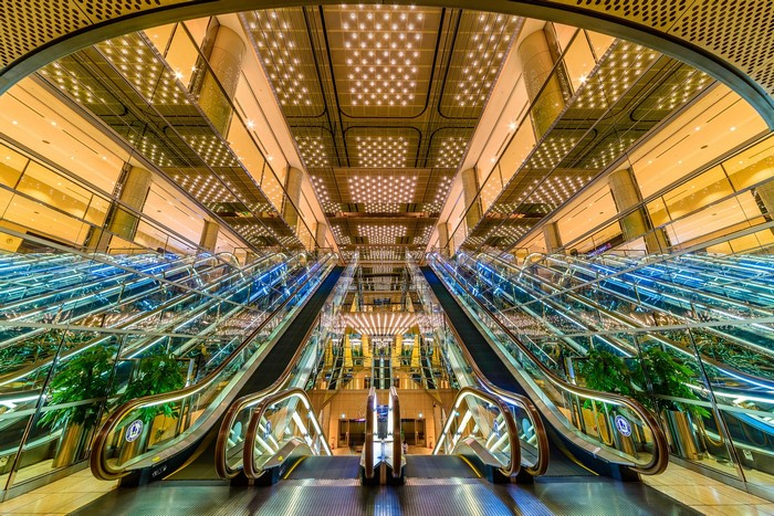 Modern escalator hall with glass railings and bright ceiling lights