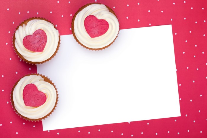 Three cupcakes with heart decorations on a polka dot background