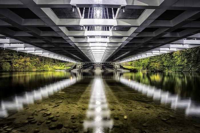 Underneath a modern bridge with reflections in the water