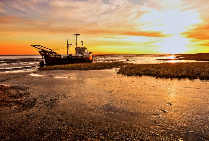 Fishing boat grounded on a beach at sunset