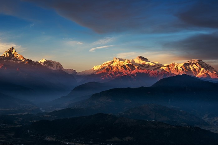 Snow-capped mountains at sunrise with dramatic clouds