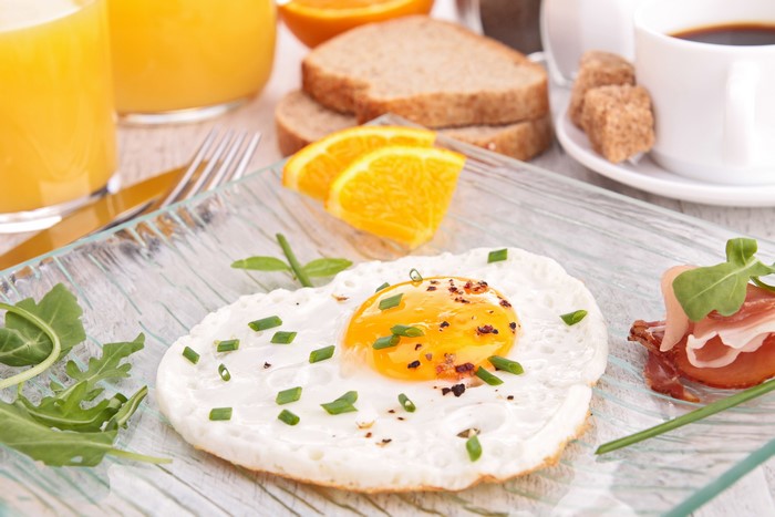 Fried egg with ham and orange slices for breakfast