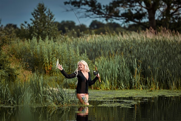 Blonde woman fishing with a rod and a fish