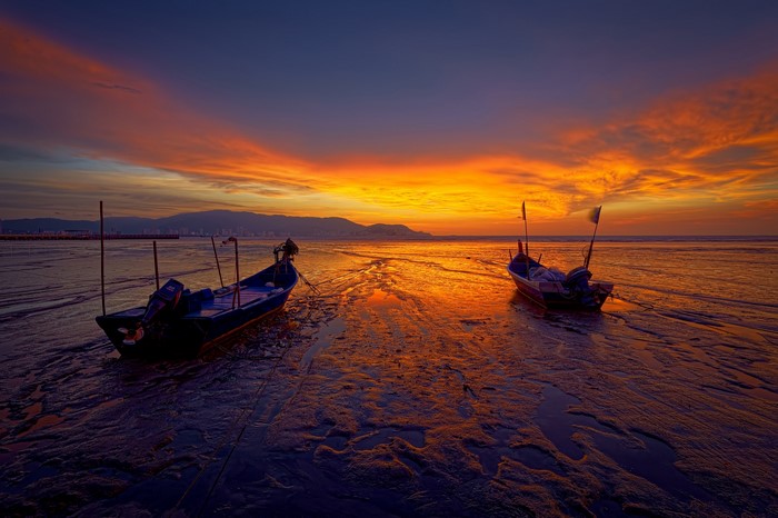 Boats on a beach during a vibrant sunset