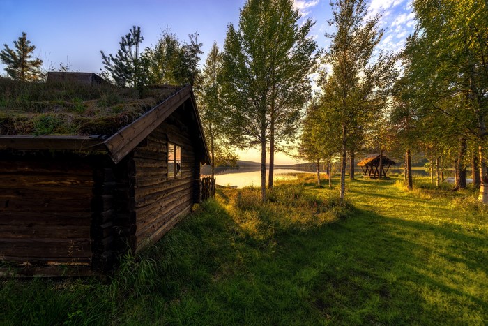 Log cabin by a lake with trees and a gazebo