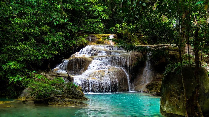 Tiered waterfall cascading into a turquoise pool in a dense forest