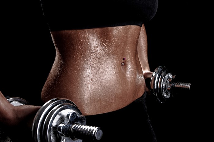 Woman with toned abs holding dumbbells
