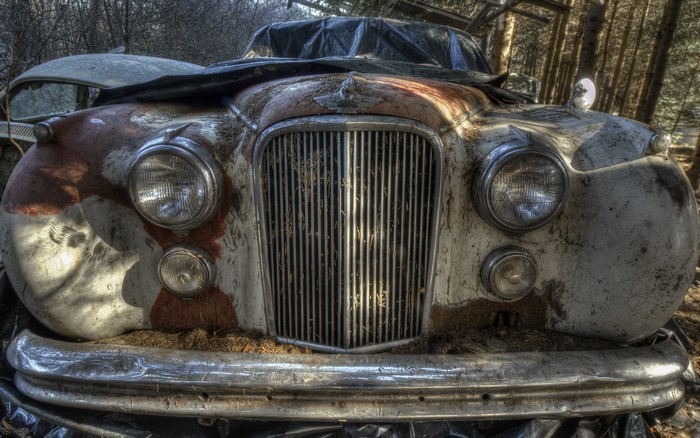 Old rusty car front with headlights and grille