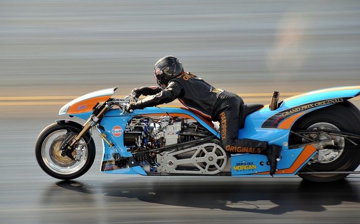Motorcyclist in black racing suit on a blue drag bike