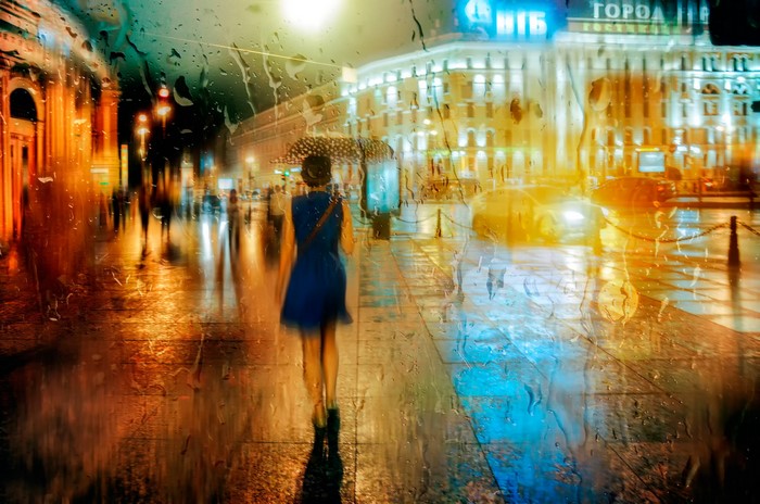 Woman with umbrella walking in St. Petersburg at night in the rain