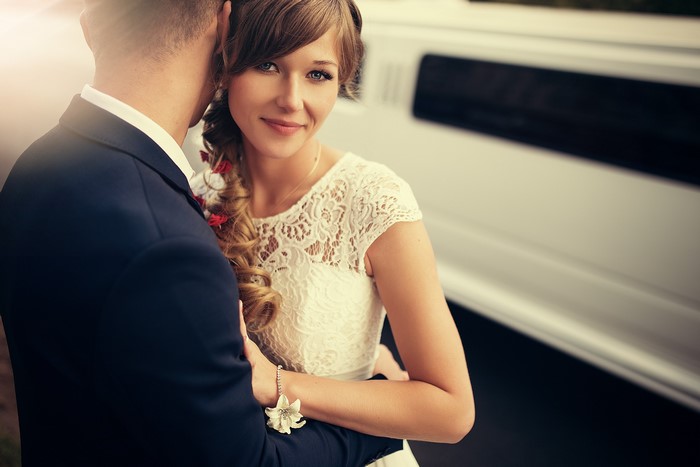Bride and groom embracing near a limousine
