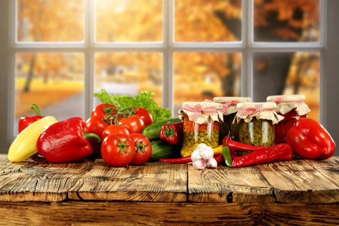 Vegetables and jars of preserves on a wooden table