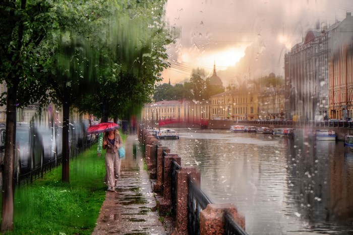 St. Petersburg canal in the rain with people walking under umbrellas
