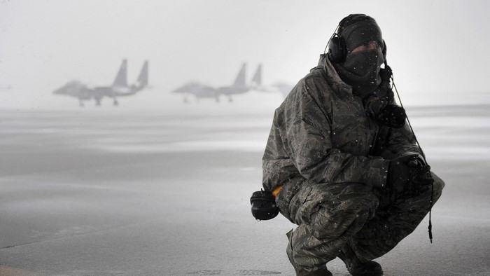 Soldier in winter gear with fighter jets in background