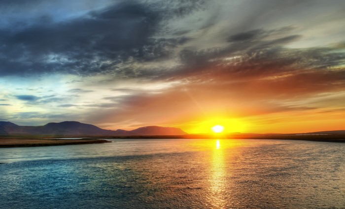 Sunset over a river with mountains
