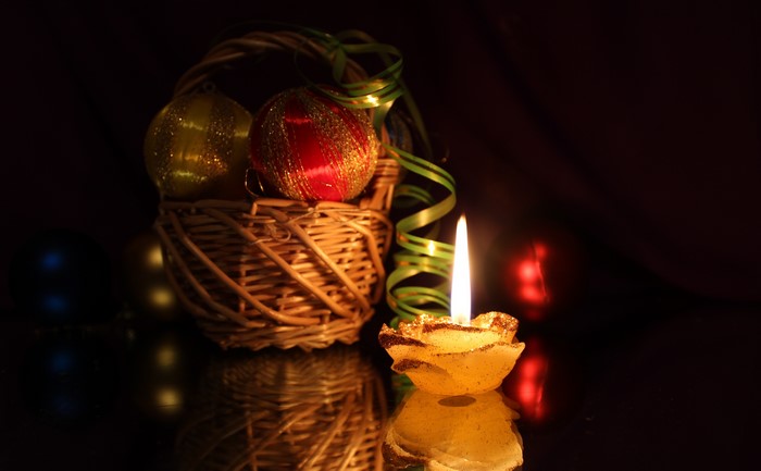 Christmas ornaments in a basket with a lit candle