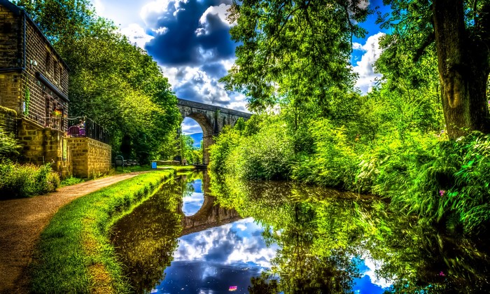 Canal bridge reflection with stone building and trees