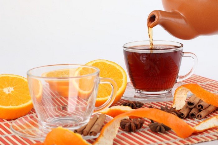Tea being poured into a cup with oranges and cinnamon