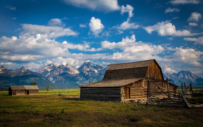 Wooden barns and mountains under a cloudy sky